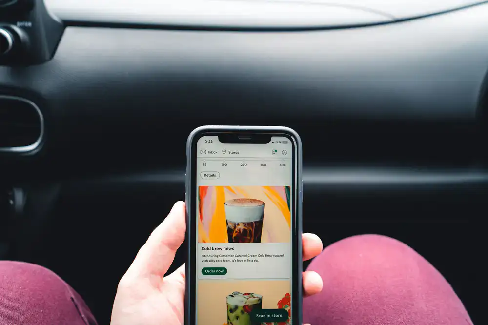 Person using a smartphone next to freshly brewed coffee, managing their subscription online